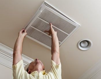 Man putting grate back on AC vent