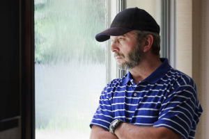 Man looking out at the rain from window